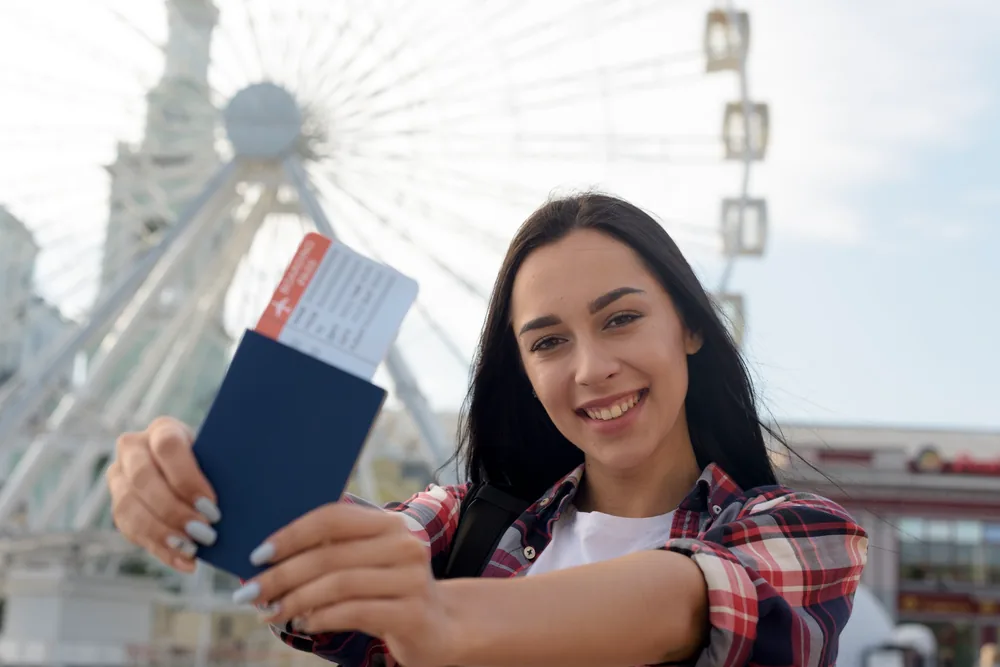 Smiling student holding a passport and boarding pass